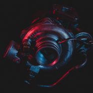 An old reconditioned car turbine, turbocharger, isolated on black with red and blue lighting.